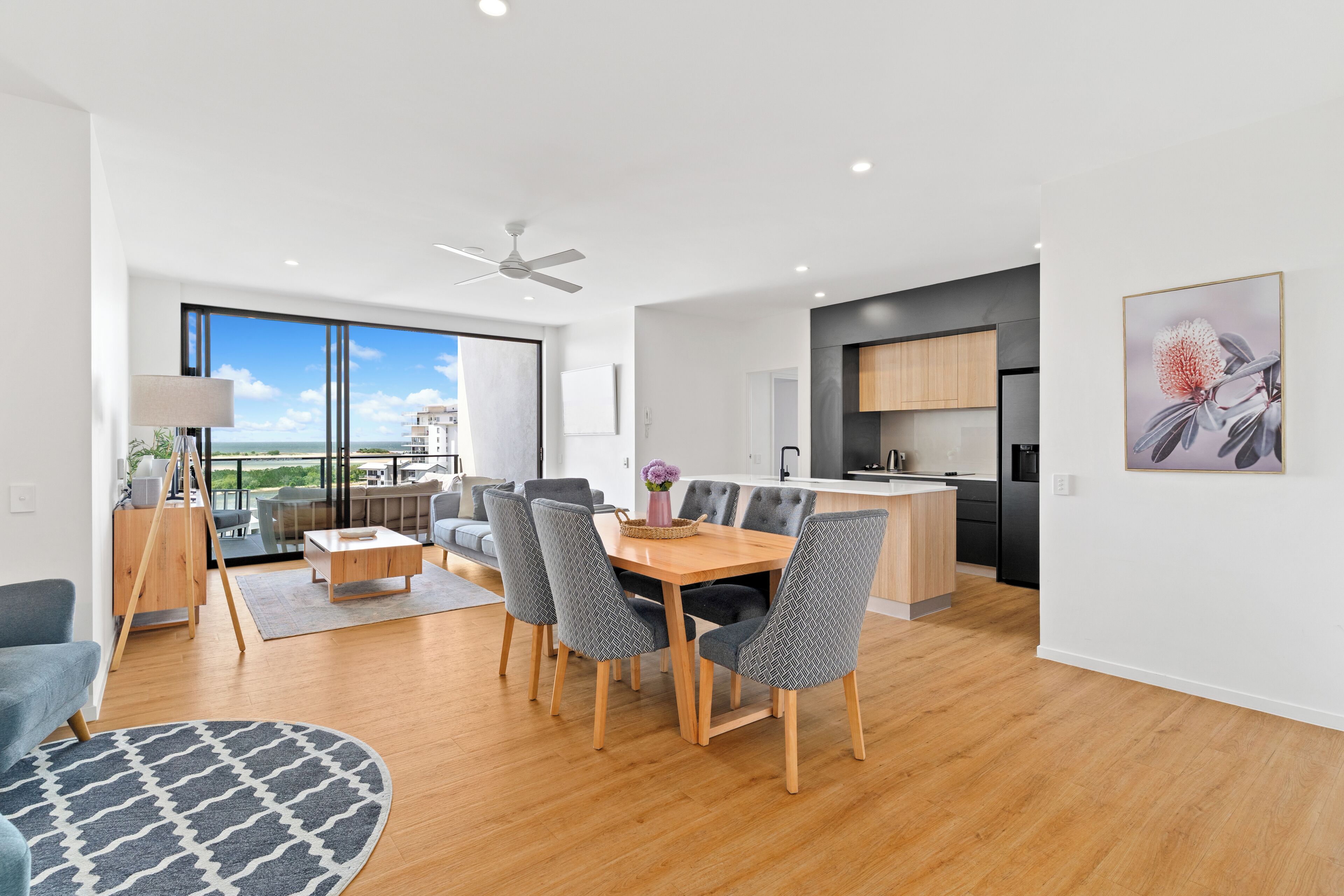 A modern apartment with a dining area, kitchen, and balcony with a view.