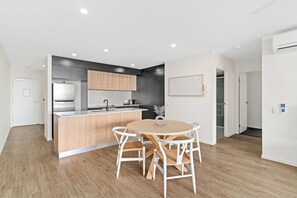 Uma cozinha moderna com uma ilha central, armários de madeira e um espaço de jantar com mesa e cadeiras redondas.