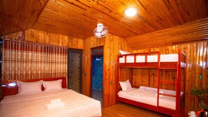 Een houten blokhut met twee eenpersoonsbedden, een houten plafond en een kleine kitchenette.