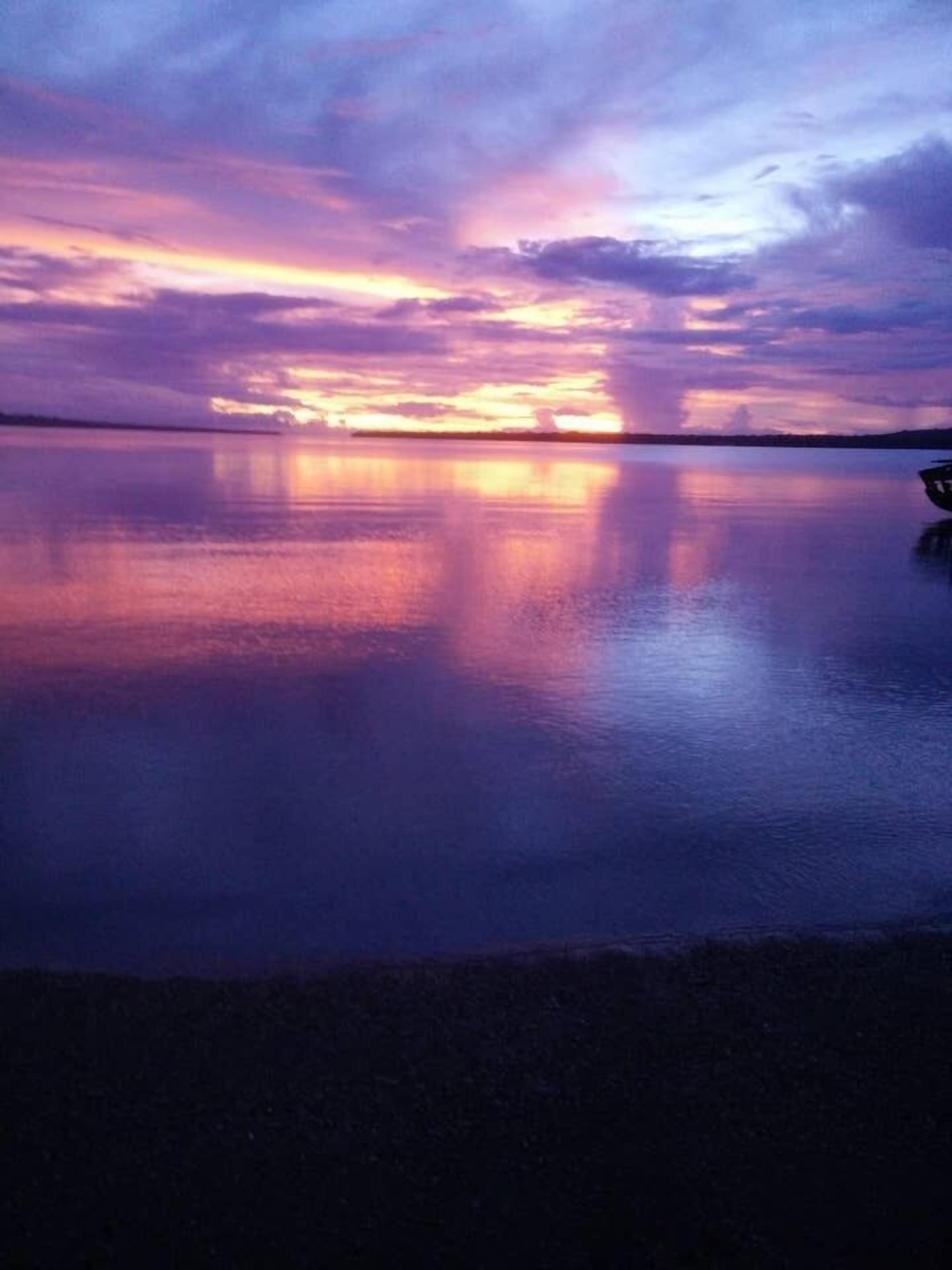 A calm body of water reflecting a sunset sky.