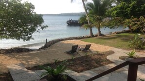 A patio with two chairs and a small table, overlooking a body of water with a boat in the distance. - Santo Seaside Villas (Luganville)