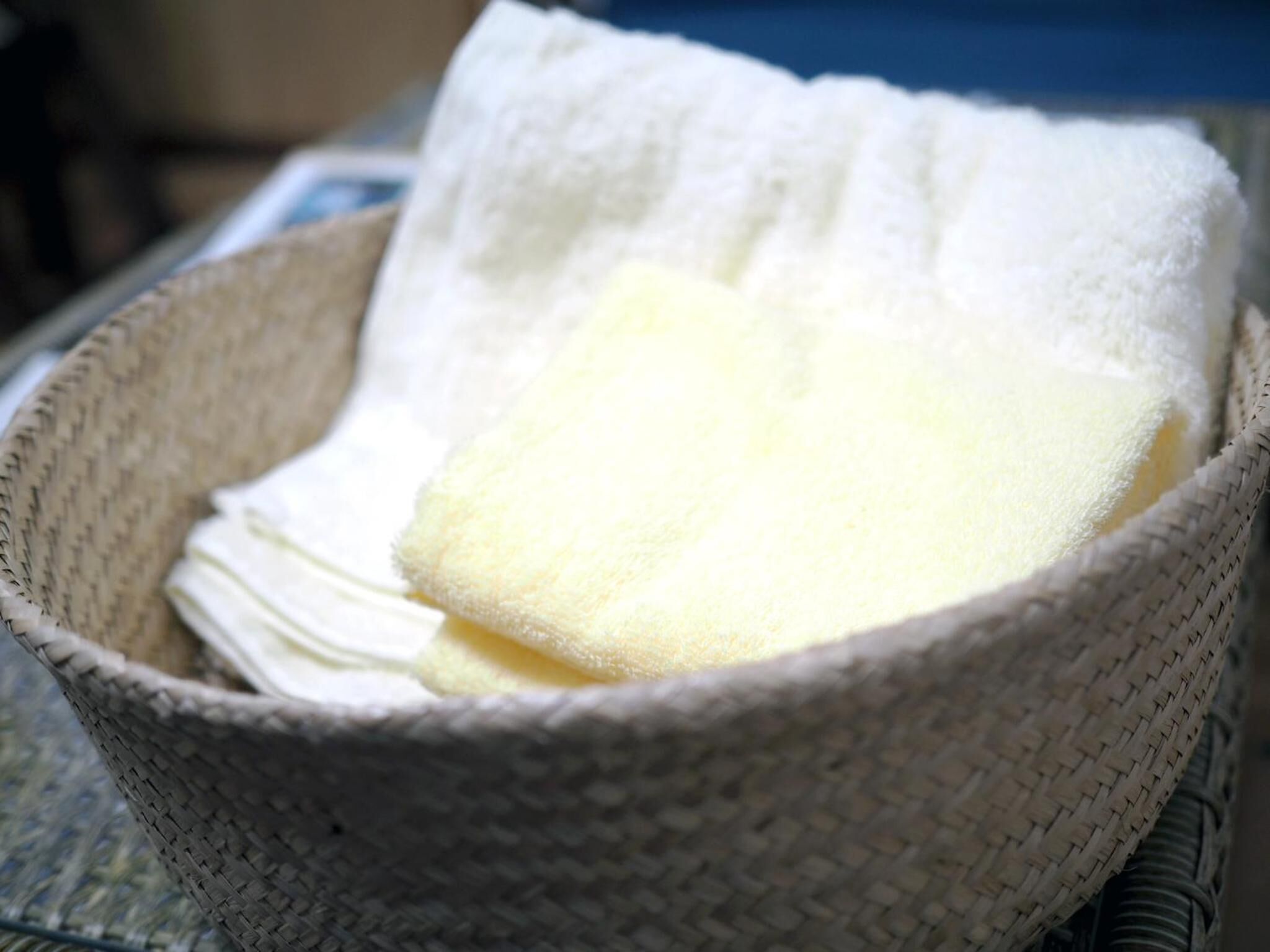 Una cesta tejida que contiene un paño blanco y un objeto blanco.