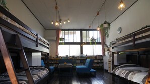 A dormitory room with bunk beds, a desk, a chair, a bookshelf, and a window with curtains. - Mikan Hotel (Mihama)