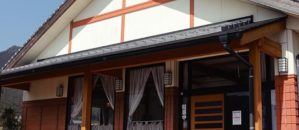 A traditional Japanese building with a wooden facade, large windows, and a covered entrance.