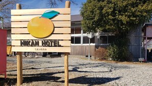 A wooden signboard for Mikani Hotel with a fruit design and Japanese text. - Mikan Hotel (Mihama)