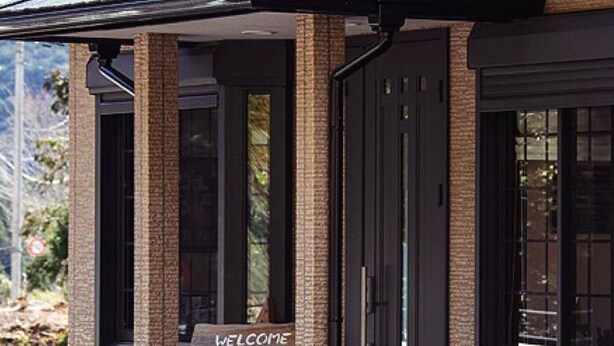 A building entrance with a 'WELCOME' sign, large glass doors, and a brick facade. - Mikan Hotel (Mihama)