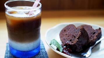 A glass of iced coffee with a straw and a plate of chocolate cake with berries.