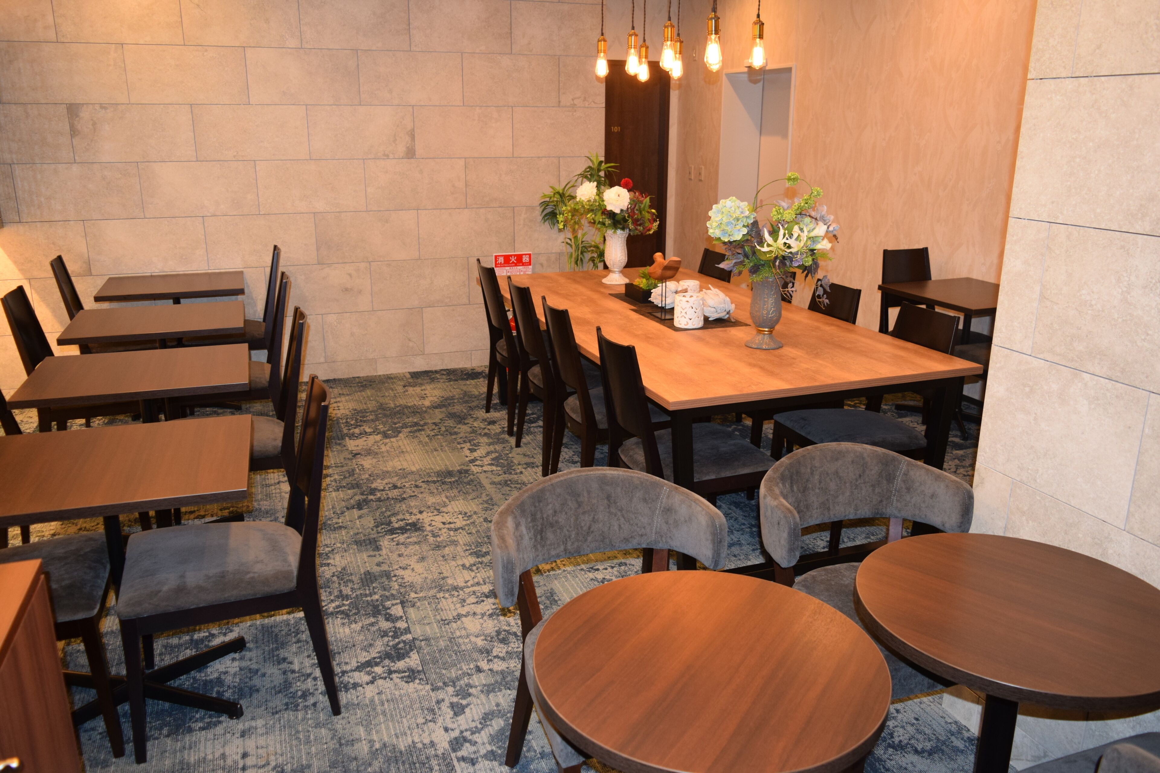 A conference room with a long wooden table, multiple chairs, and a decorative vase with flowers.