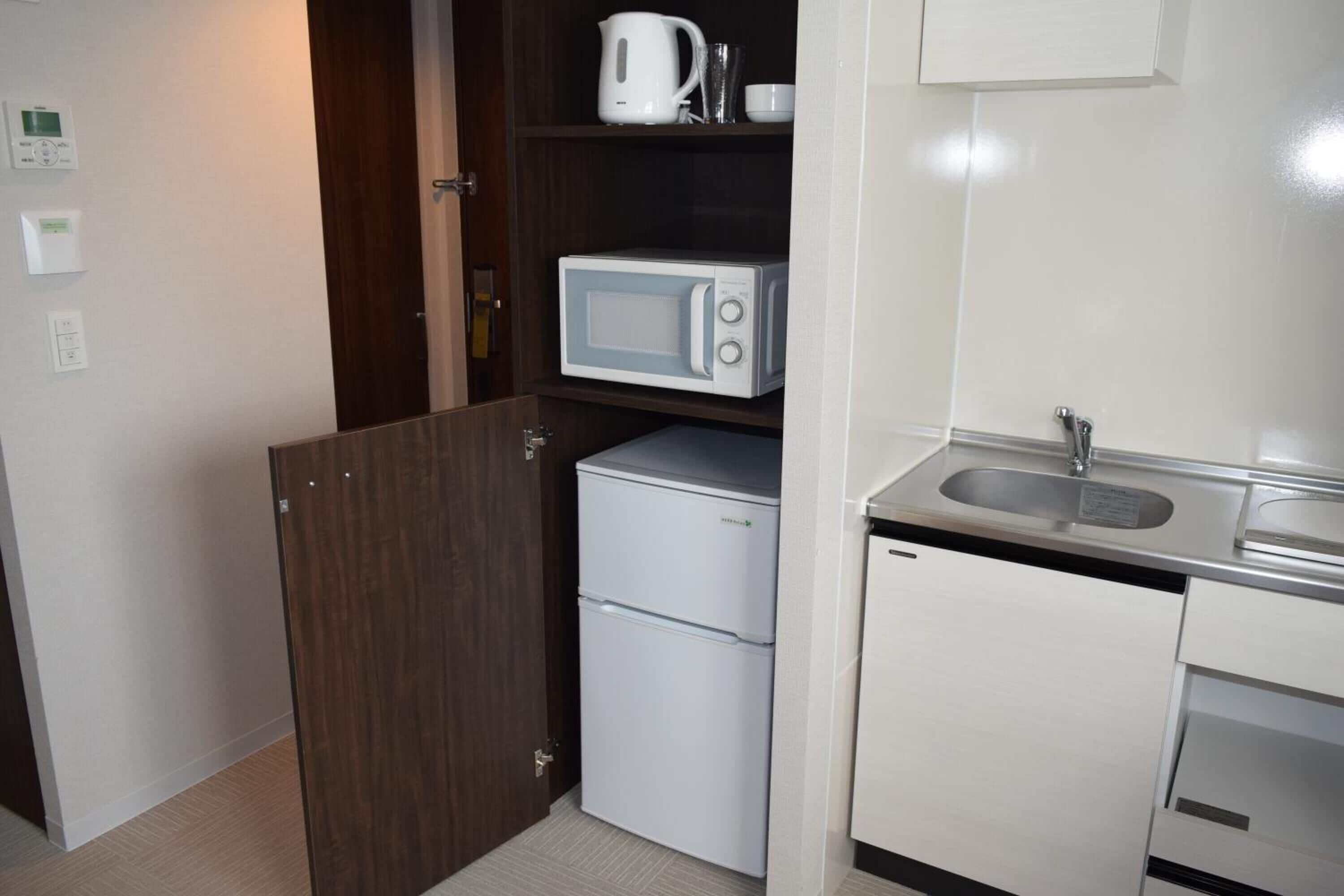 A compact kitchenette with a microwave, a small refrigerator, and a sink.