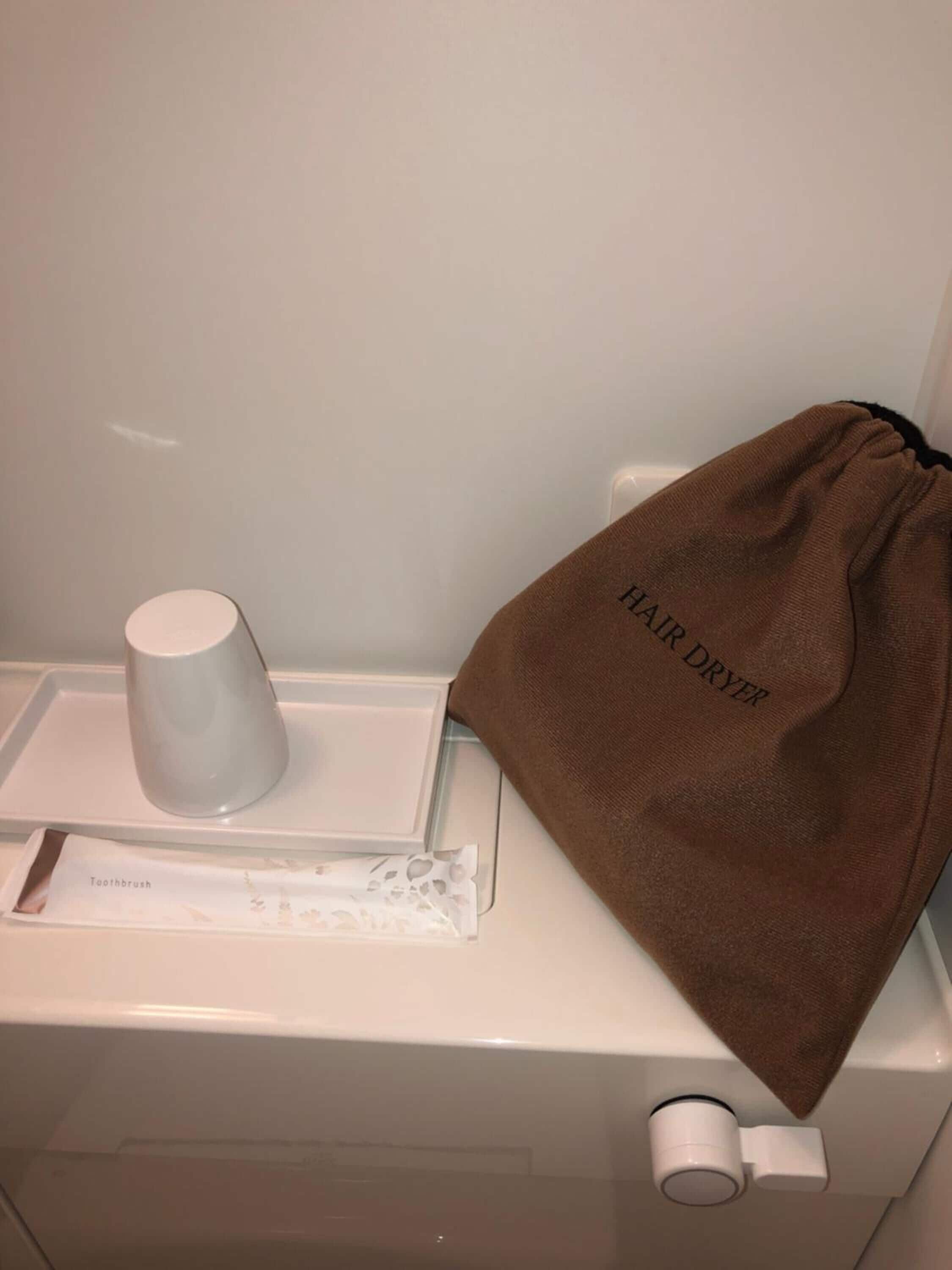 Ett badrum med ett vitt handfat, en brun handduk och en vit mugg.