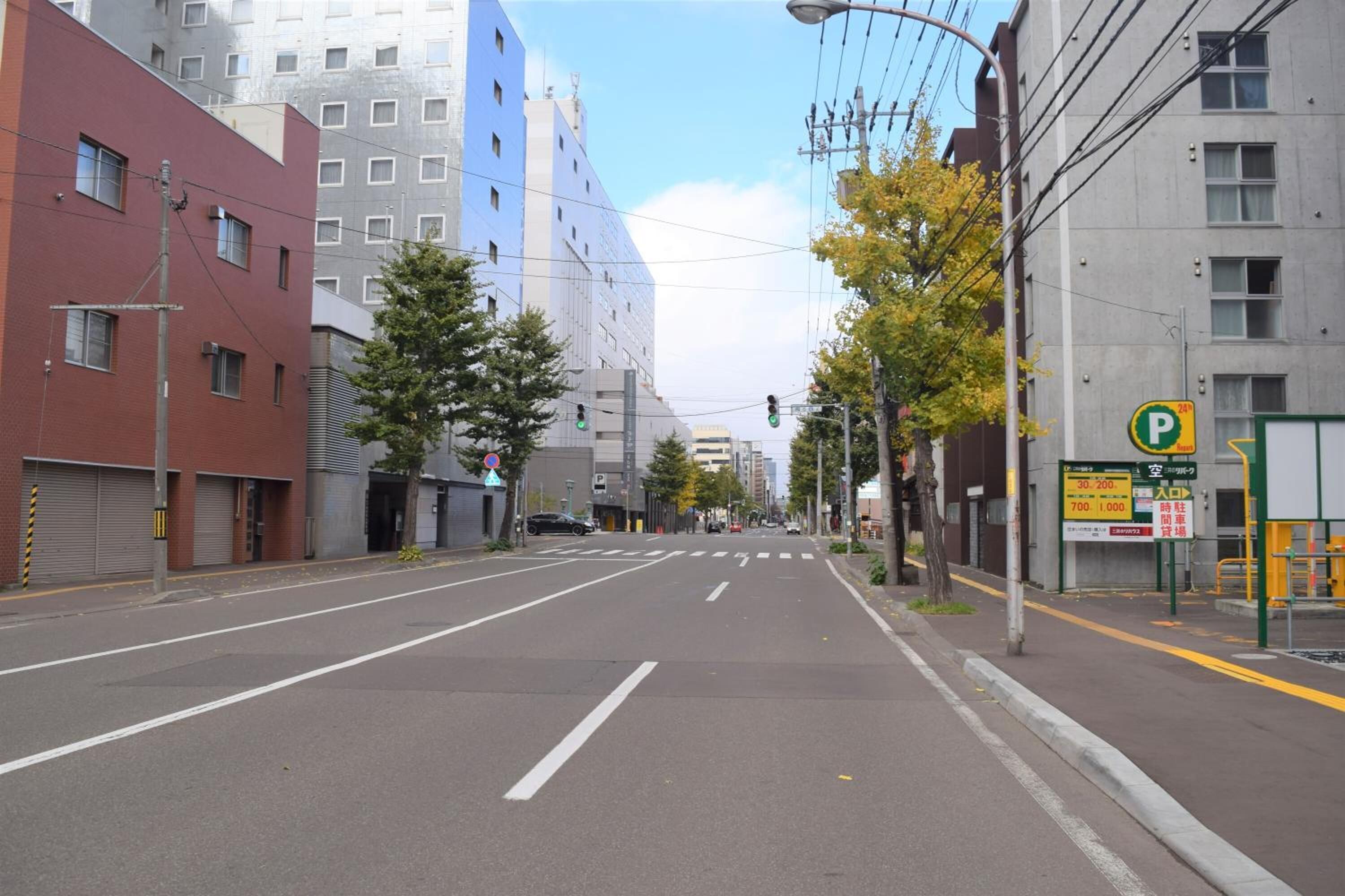 Un carrer amb edificis, un senyal de pàrquing i semàfors.