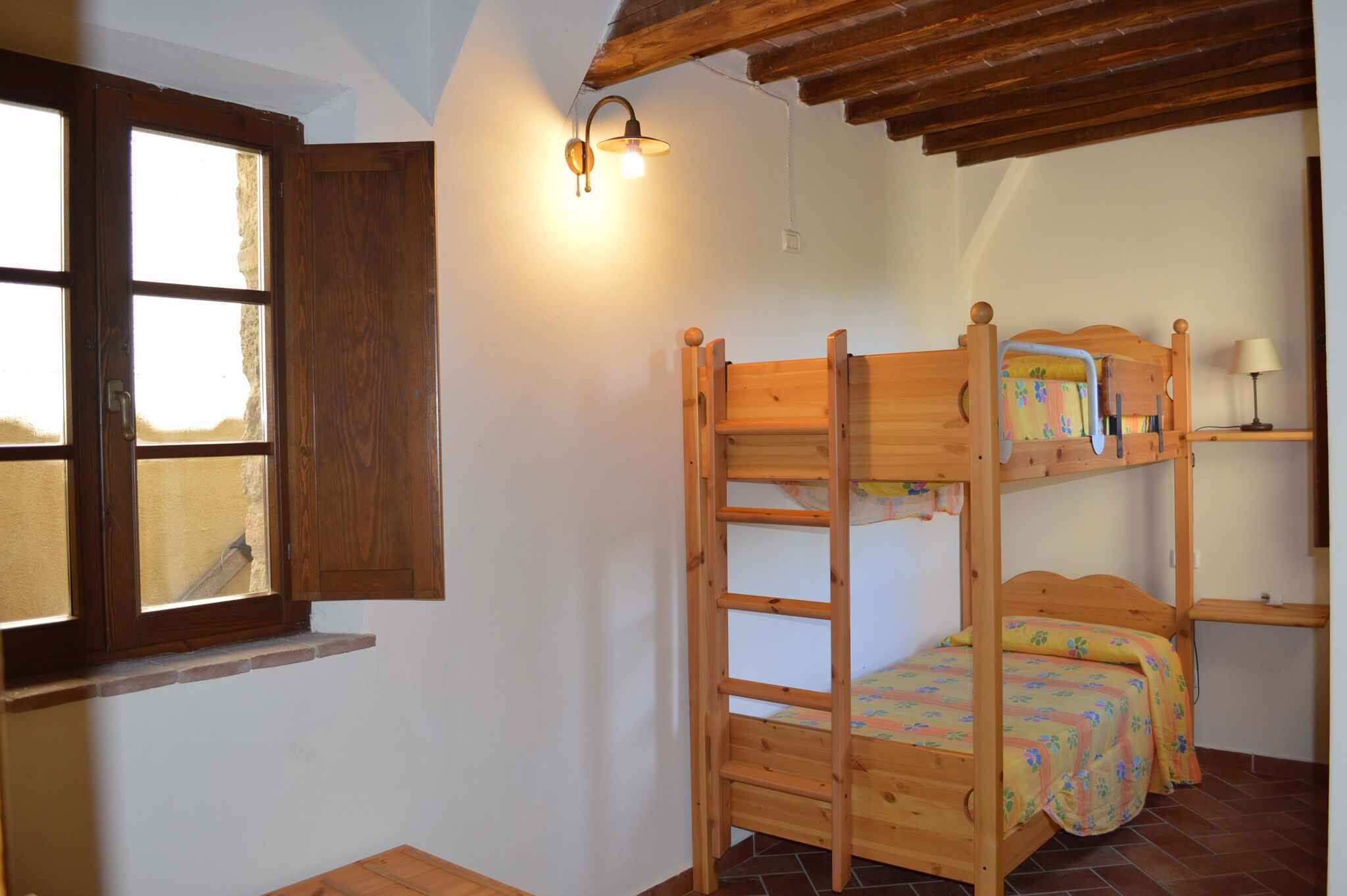 Camera con letto a castello, una scala in legno, una finestra con cornice in legno e un punto luce fissato al muro.