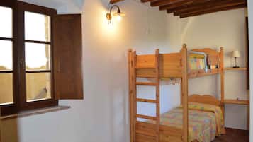 Camera con letto a castello, una scala in legno, una finestra con cornice in legno e un punto luce fissato al muro.