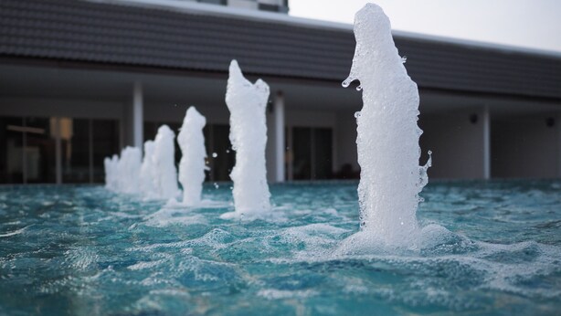 Una piscina con múltiples chorros de agua en un edificio moderno.