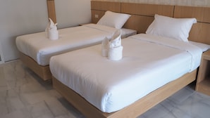 Habitación de hotel con dos camas individuales, cada una con ropa blanca y toallas.