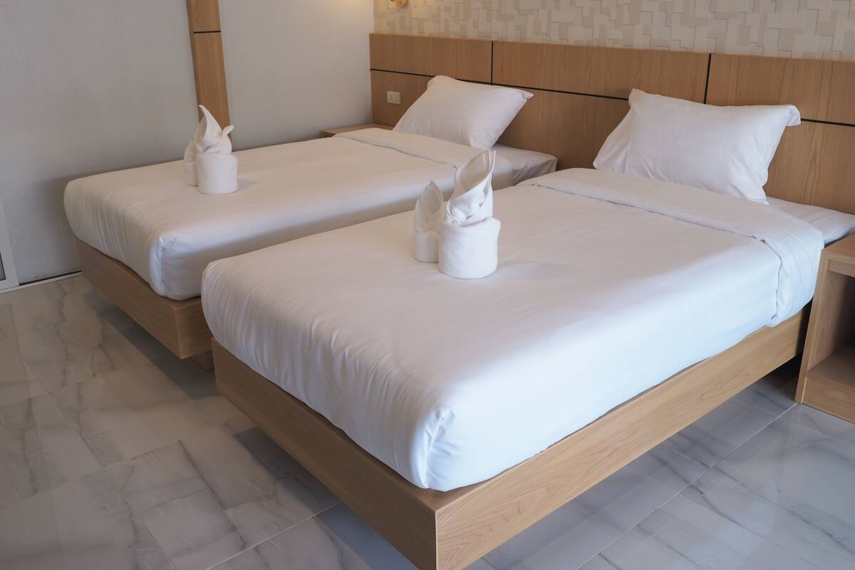 A hotel room with two single beds, each with white linens and towels.