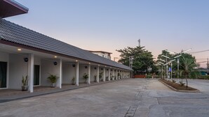 Un hotel con un espacio exterior techado, habitaciones numeradas y un camino pavimentado.