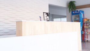 Un área de recepción moderna con un mostrador de madera, una pared con diseño y una máquina expendedora azul.