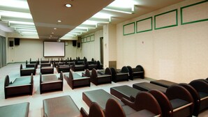 A conference room with rows of black chairs and tables, a projector screen, and a large whiteboard on the wall. - Sauna Capsule Hotel Core 21 - Caters to Men (Tokyo)