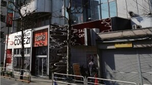 A modern hotel with a glass facade, multiple floors, and a prominent 'Sakura Capsule Hotel' sign. - Sauna Capsule Hotel Core 21 - Caters to Men (Tokyo)