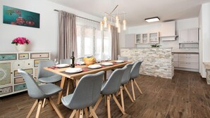 Et moderne spiseområde med et træbord, grå polstrede stole og en lysekrone.