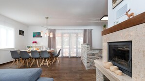 En moderne stue med pejs, spiseplads og et stort vindue med gardiner.
