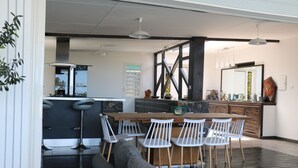 Een moderne keuken met een centraal eiland, witte barkrukken en een zithoek met een grijze bank en houten stoelen.