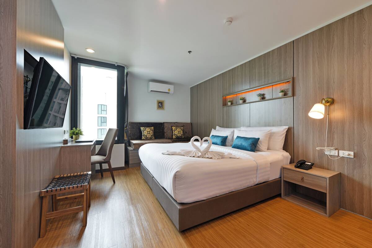 A modern hotel room with a large bed, a desk, and a chair.
