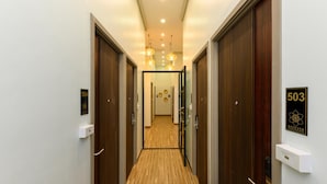 A hotel corridor with wooden flooring, numbered doors, and pendant lighting. - StayAt Bedever Bangkok Hotel (Bangkok)
