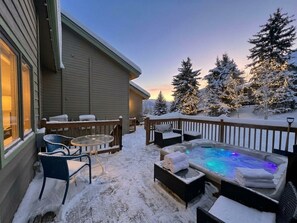 A snow-covered deck with a hot tub, outdoor seating, and snow-covered trees. - Bright Mountain Retreat | Hot Tub | Bunk Room | 5 Baths | Sleeps 13 (Avon)