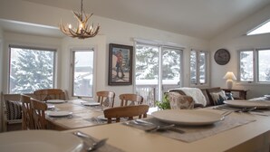 A dining area with a wooden table set for four, surrounded by chairs, with a chandelier above. - ☞Sunny & Spacious 2 King 2 Queen in the heart of the Vail❅Valley⛷ (Avon)