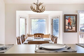 A dining area with a table set for six, a chandelier, and a painting on the wall. - Bright Mountain Retreat | Hot Tub | Bunk Room | 5 Baths | Sleeps 13 (Avon)