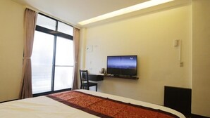 A hotel room with a bed, a desk, a television, and a large window with curtains. - Flower Bed&Breakfast is now Ikegami (Chishang)