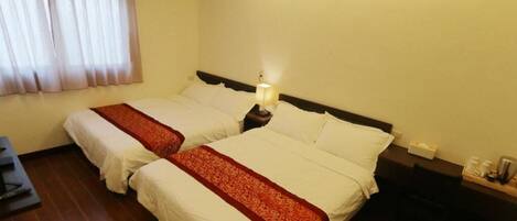 Quarto de hotel com duas camas, uma escrivaninha, uma cadeira e uma mesa de cabeceira com abajur.