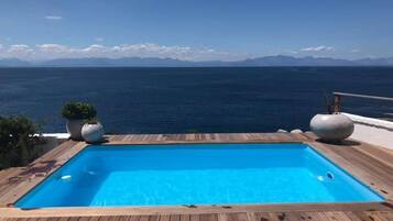 Een buitenzwembad, ligstoelen bij het zwembad