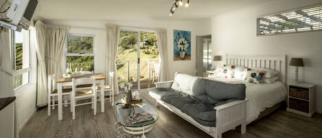 A bedroom with a bed, a sofa, a glass coffee table, a desk, and a chair.
