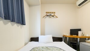 A hotel room with a bed, a desk with a computer, a telephone, and a small refrigerator.