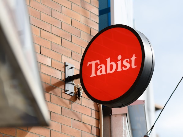 A red sign with the word "Tabist" on a brick wall. - Tabist Silk Hotel Nakatsugawa (Nakatsugawa)