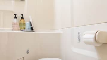 A small, modern bathroom with a toilet, a sink with a mirror, and a toilet paper holder.