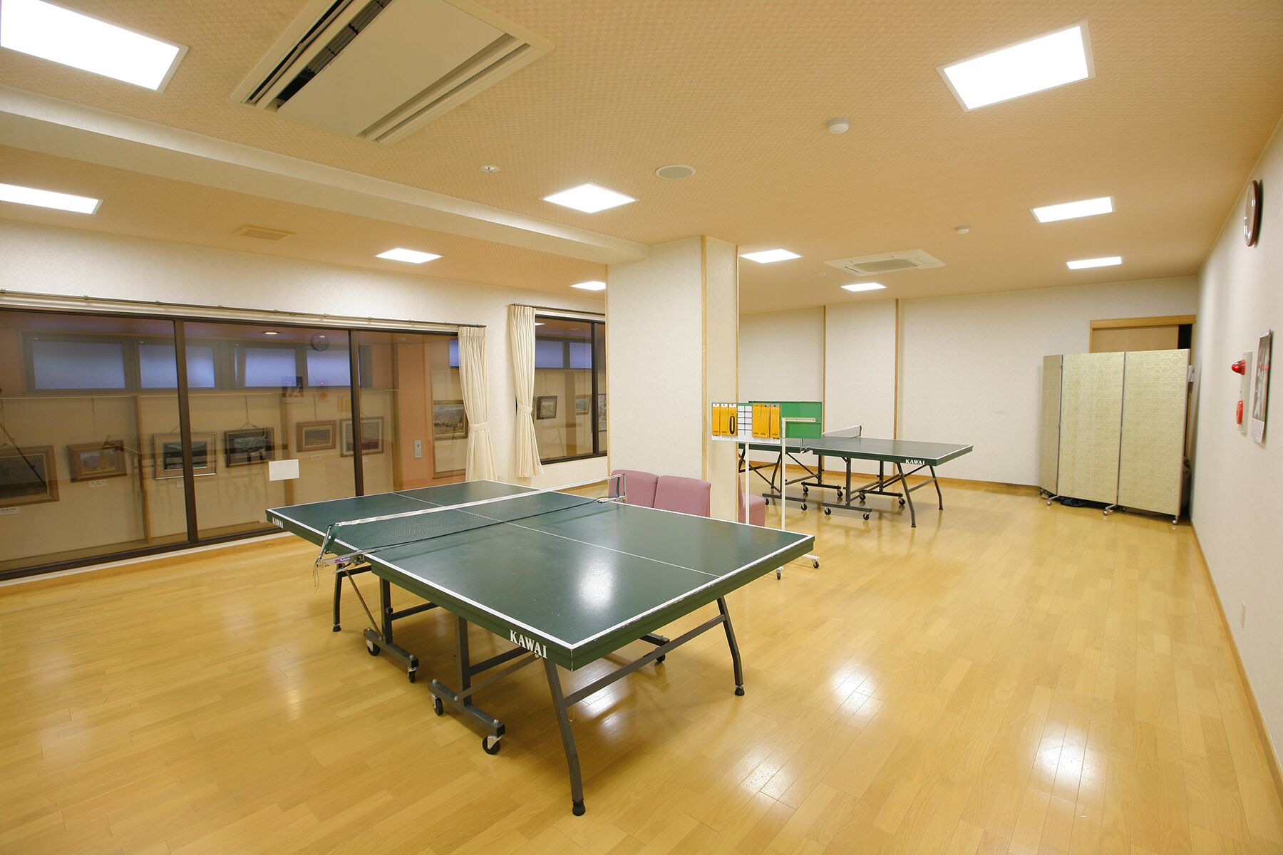 A spacious room with a ping pong table, another table, and a cabinet.