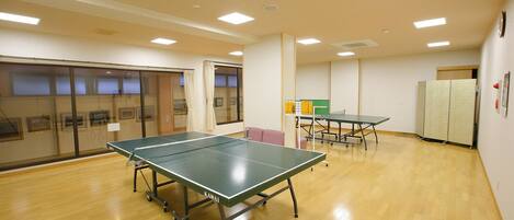 A spacious room with a ping pong table, another table, and a cabinet.
