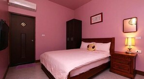 Un dormitorio con cama, mesita de noche con lámpara, armario y una puerta con cerradura.