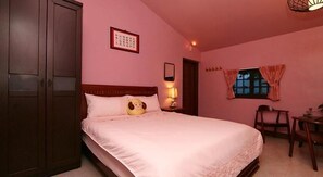 Un dormitorio con cama, mesita de noche, silla, armario y ventana con cortinas.