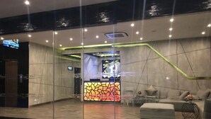 A modern lobby with a reception desk, seating area, and a glass partition. - The TJ Resort (Pattaya)
