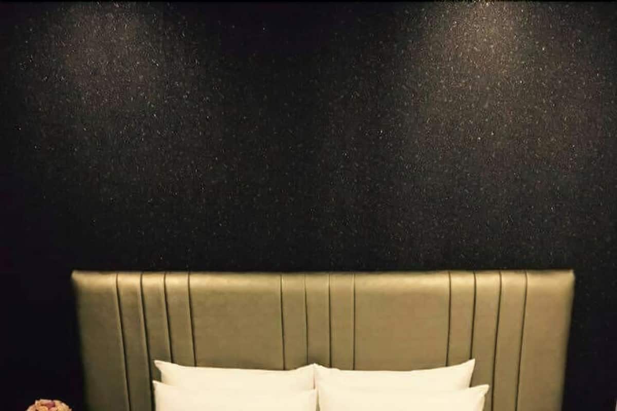 A neatly made bed with a heart-shaped pillow arrangement and a heart-shaped pillow on the bed.