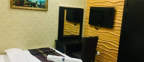 Een hotelkamer met een bed, een bureau, een stoel, een televisie en een schilderij aan de muur.