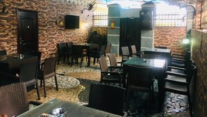 Un restaurante con paredes de ladrillo, pisos de baldosas y diferentes opciones de asientos, incluyendo mesas y sillas.