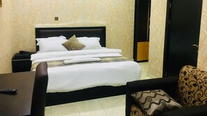 Habitación de hotel con cama, mesita de noche, silla, aire acondicionado y puerta.