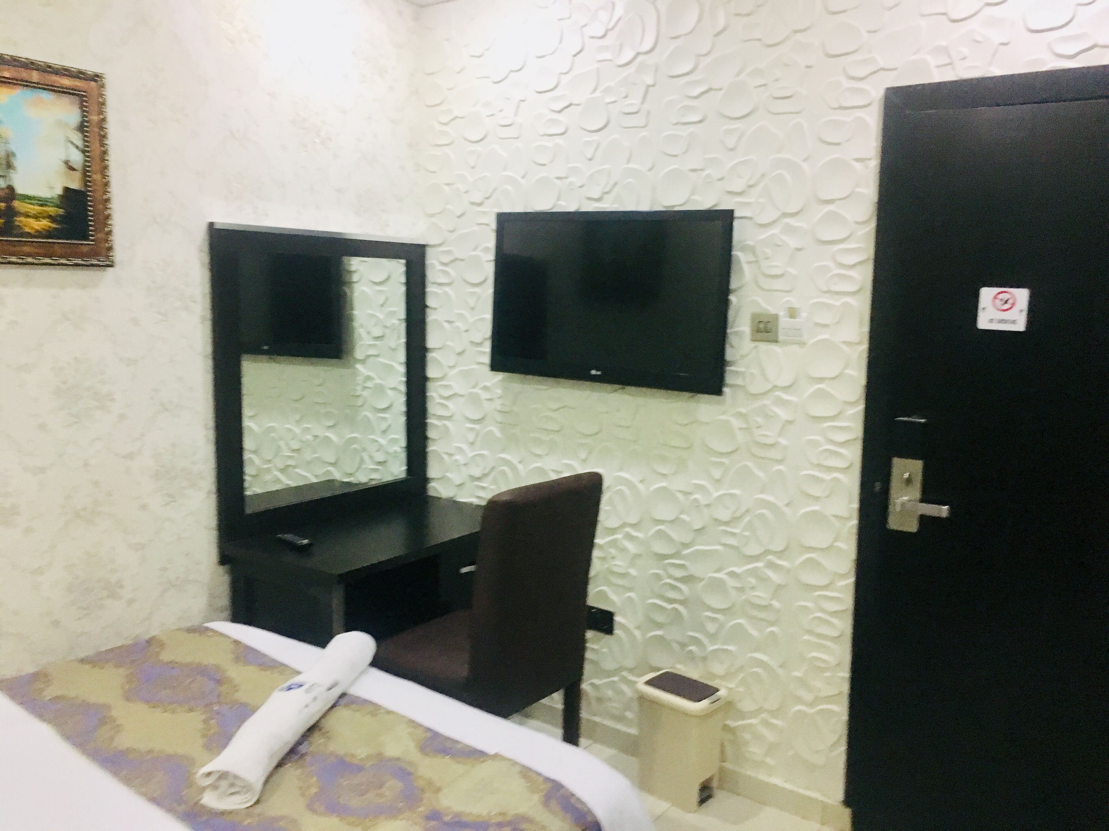 Une chambre d’hôtel avec un lit, un bureau et une chaise, une télévision et une porte.
