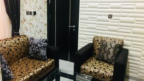 Una sala con puerta negra, papel tapiz floral y sofás estampados.